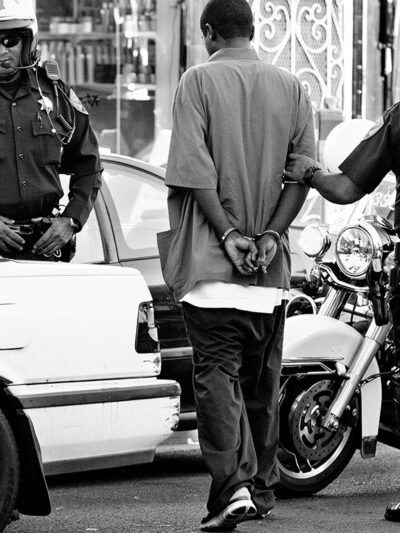 Police surrounding handcuffed man