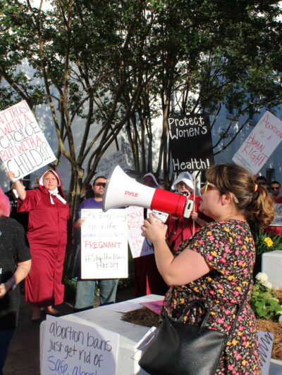 woman at megaphone chanting during statehouse protest