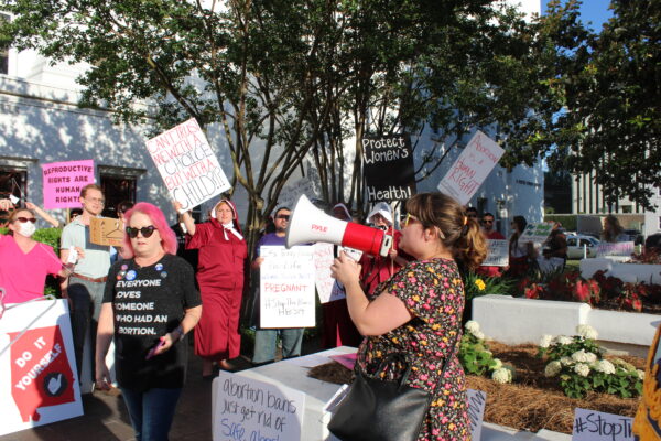 woman at megaphone chanting during statehouse protest