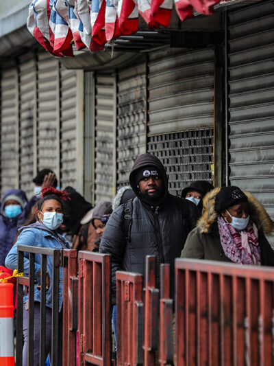 Customers in masks line up outside a grocery store in Brooklyn, NY, waiting to enter after other shoppers have left, because of social distancing efforts during the coronavirus outbreak.