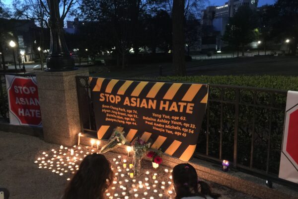 "stop asian hate" banner and candles at a local vigil
