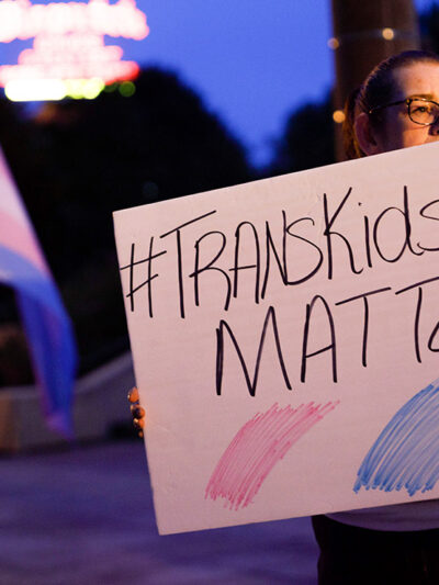 A transgender rights advocate holds a sign saying #TransKidsLivesMatter.