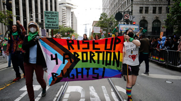 People holding a rainbow flag banner reading "Rise Up 4 Abortion Rights" while marching at the 2022 San Francisco Pride parade of 2022.