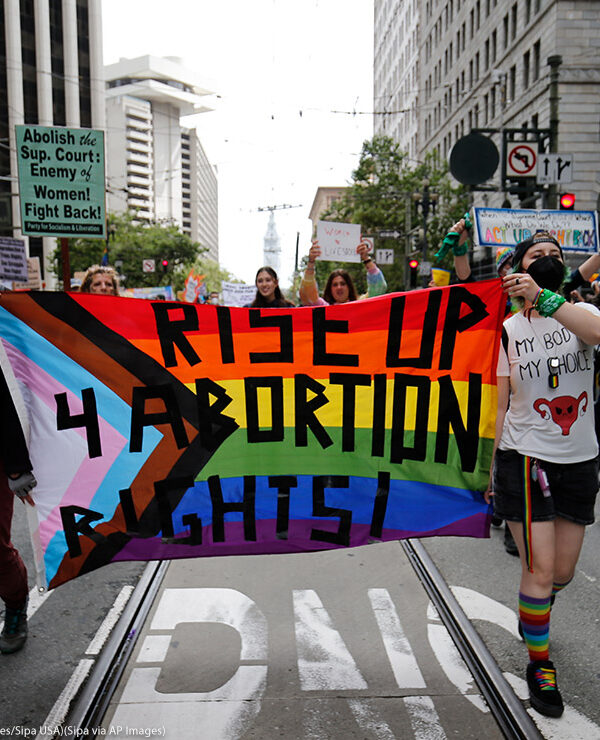 People holding a rainbow flag banner reading "Rise Up 4 Abortion Rights" while marching at the 2022 San Francisco Pride parade of 2022.