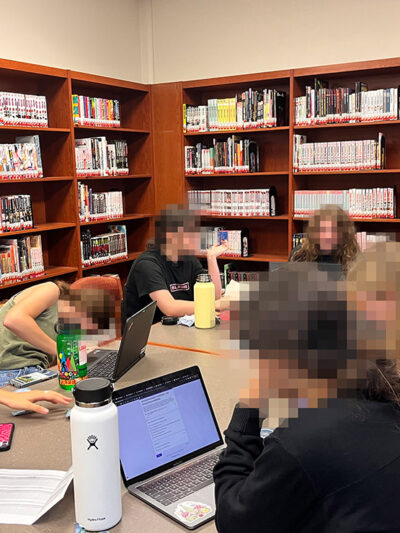 A group of students reading around a desk.