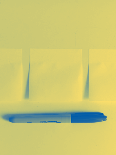 A photo of sticky notes on a table with a pen below.