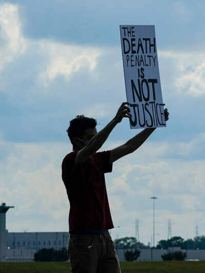 A man holding a sign that says "Death Penalty is Not Justice."