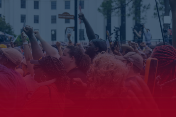 image of people with fists raised on a blue field with a red gradient coming up from the bottom