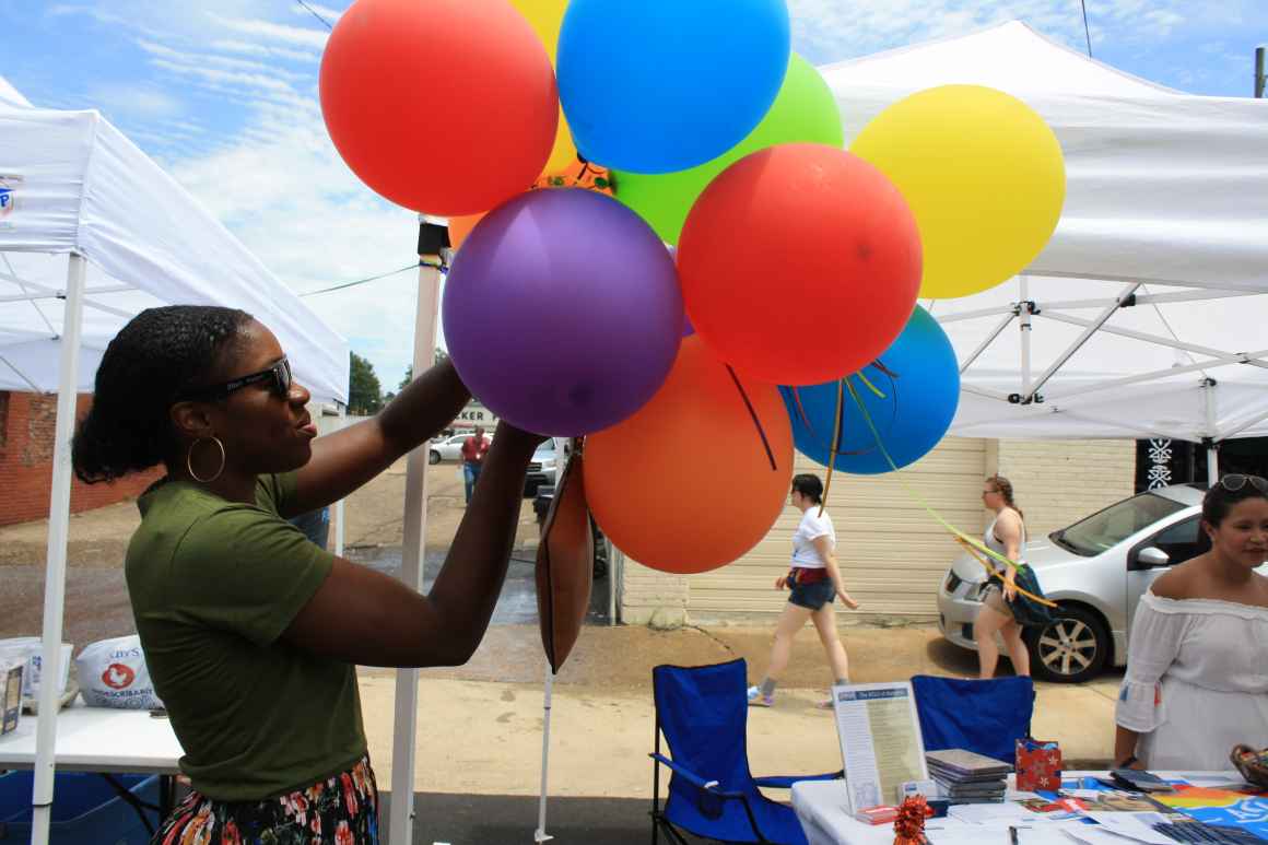 tying multi-colored balloons to table for pride