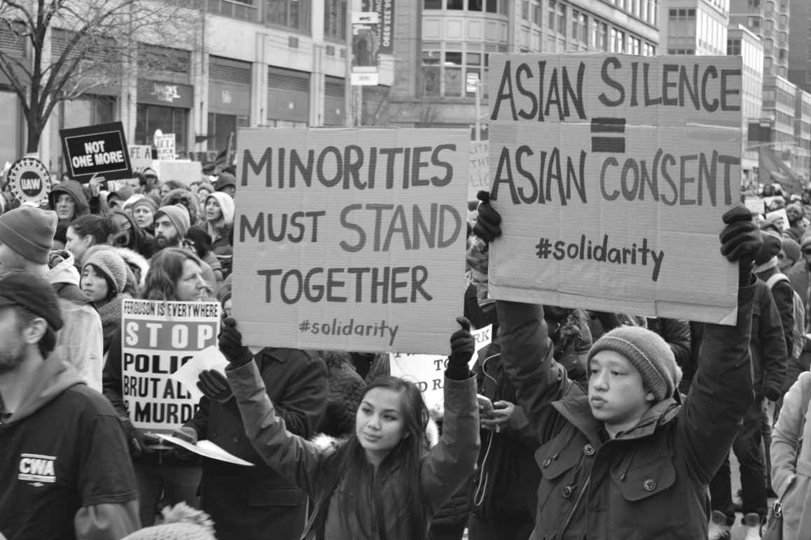 protesters hold sign says "asian silence = asian consent"