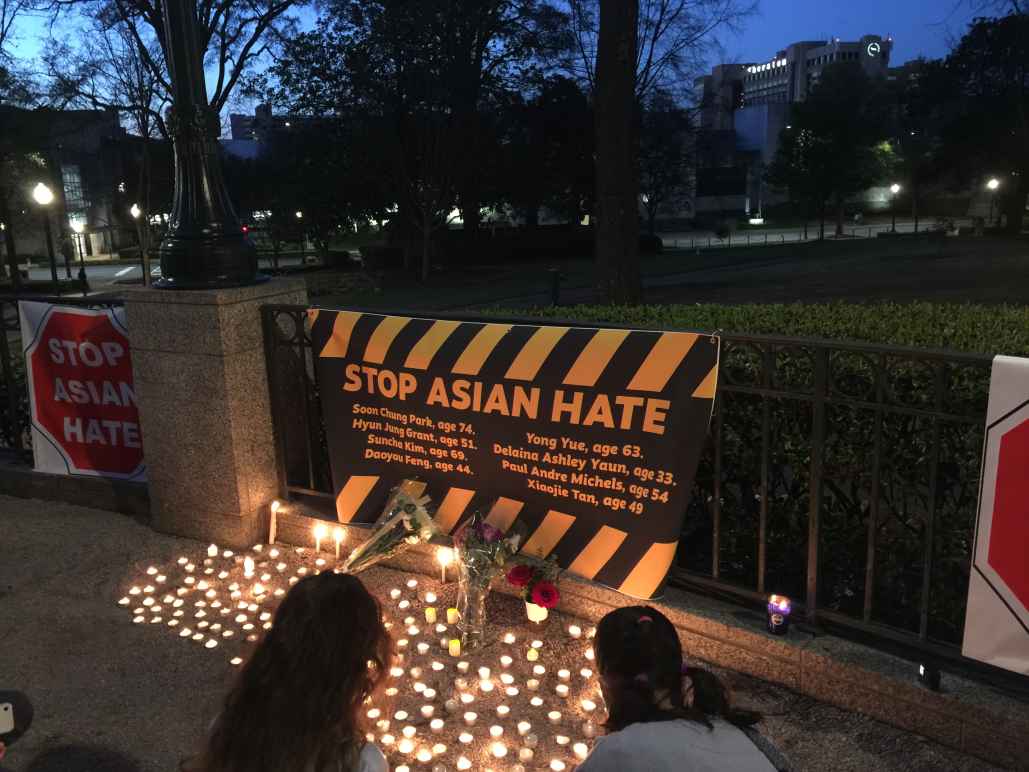 "stop asian hate" banner and candles at a local vigil