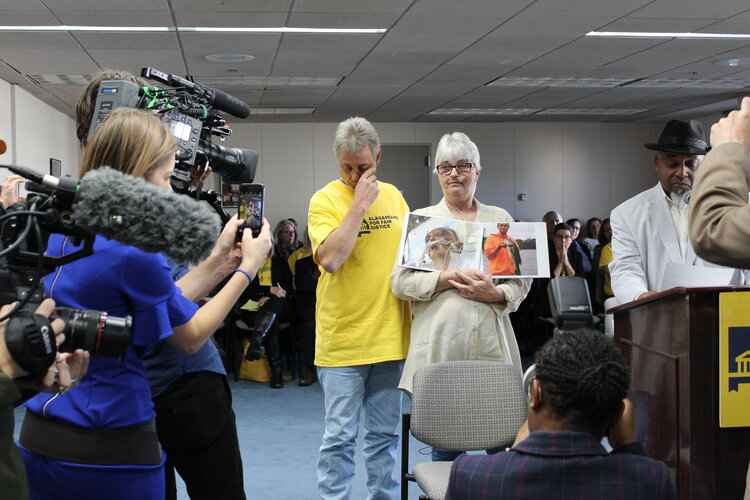 Sandy Davis holds picture of son in front of media