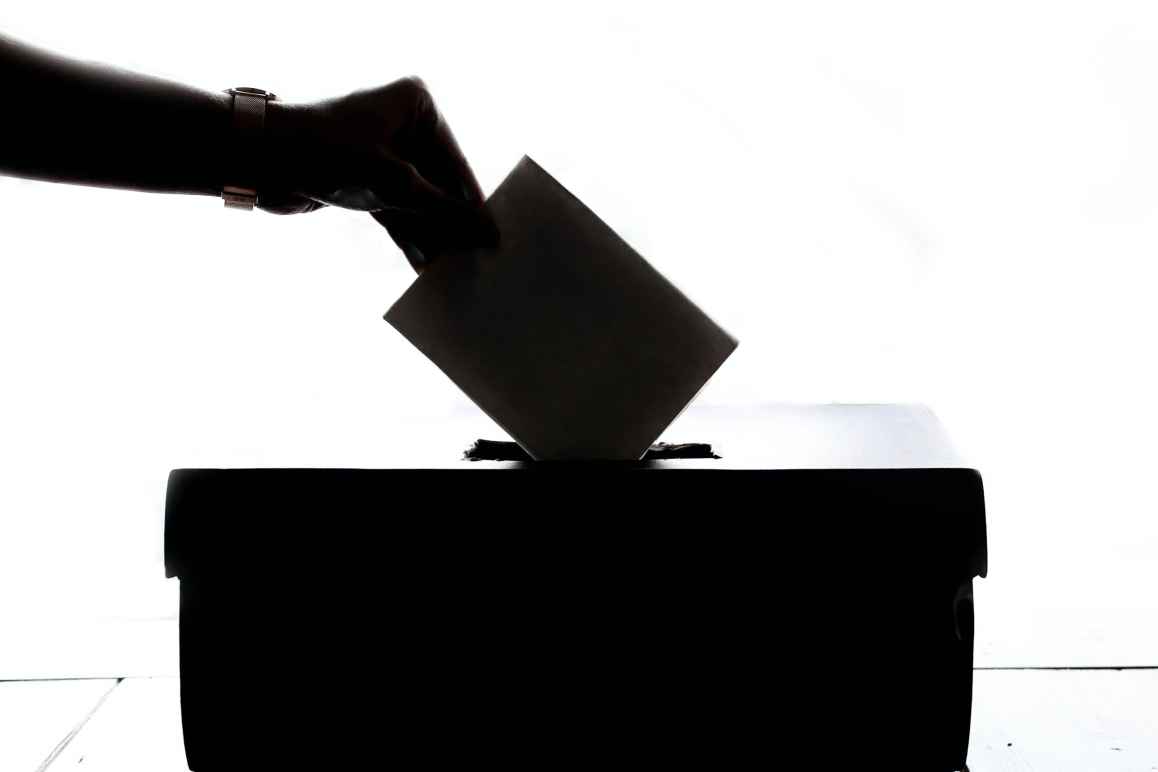 Hand dropping ballot into ballot box.