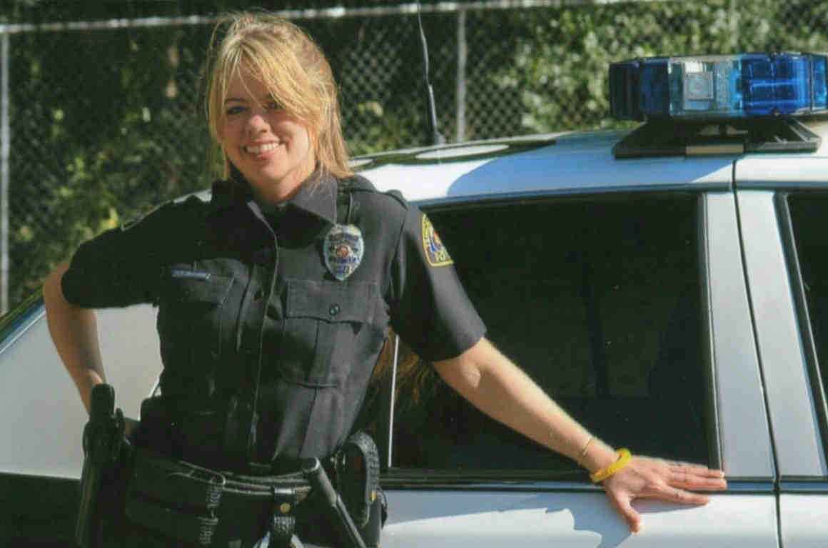 Officer Stephanie Hicks in uniform standing by police car