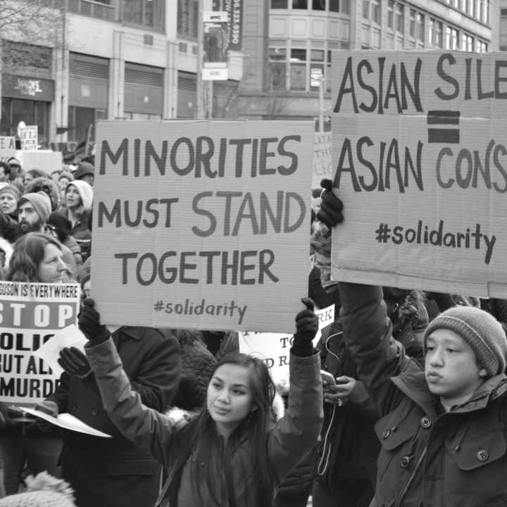 protesters hold sign says "asian silence = asian consent"