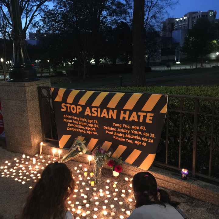 "stop asian hate" banner and candles at a local vigil