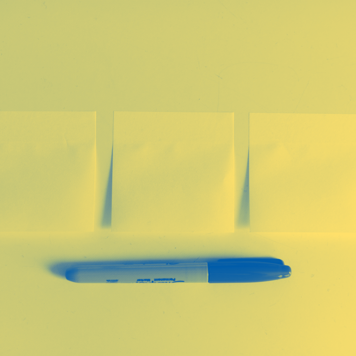 A photo of sticky notes on a table with a pen below.