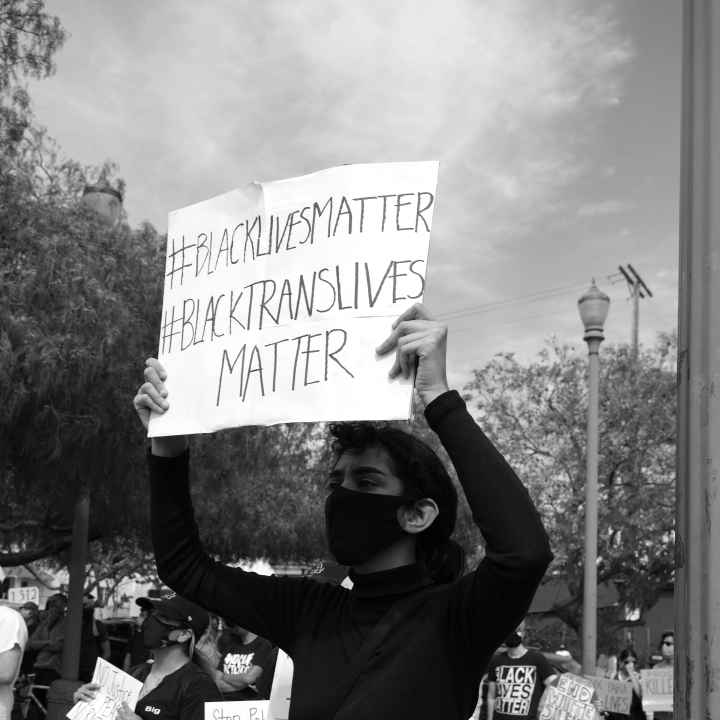 Person with #BlackLivesMatter & #BlackTransLivesMatter Sign - Mike Von
