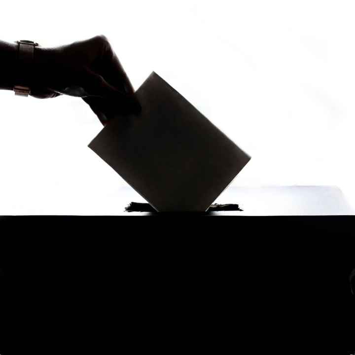 Hand dropping ballot into ballot box.