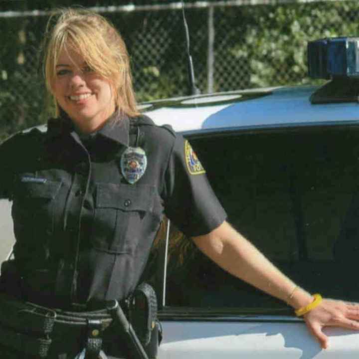 Officer Stephanie Hicks in uniform standing by police car
